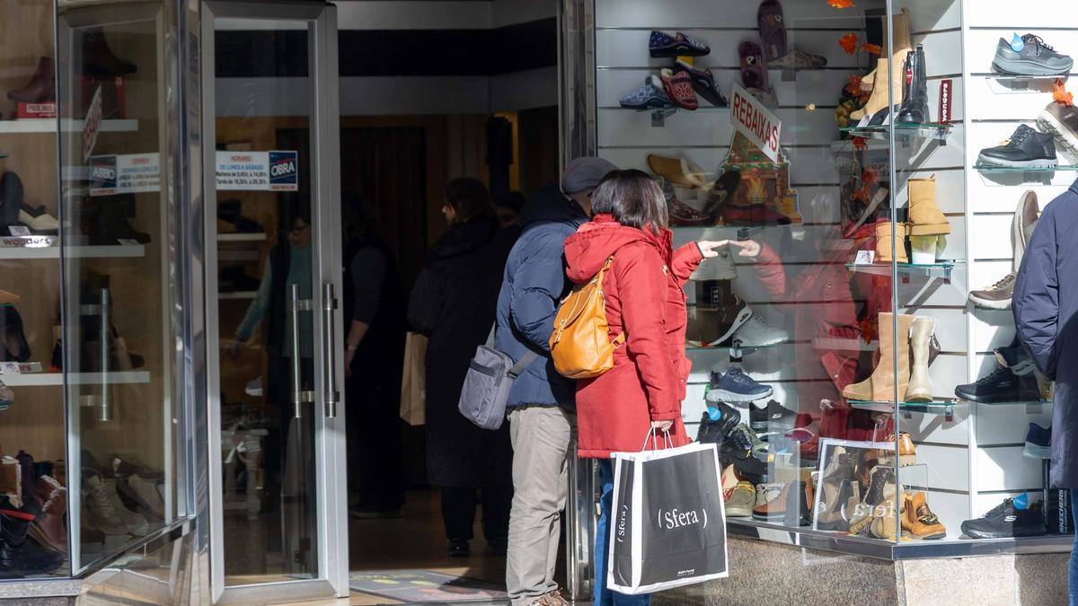 Dos personas ante un escaparate de un comercio del Ensanche, en el primer día de Rebajas.