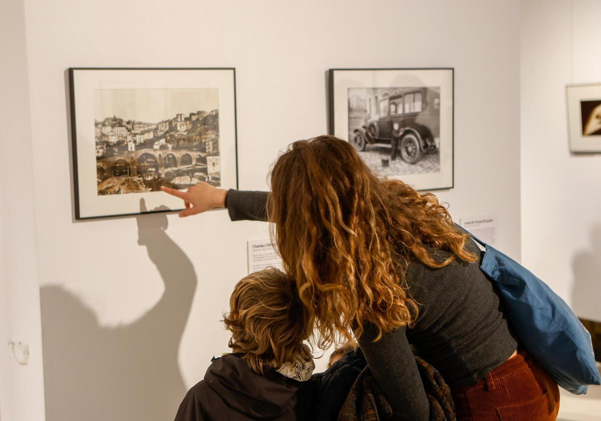 Una mare ensenya al seu fill la còpia de la fotografia més antiga de Manresa que conserva el museu, datada el 1860