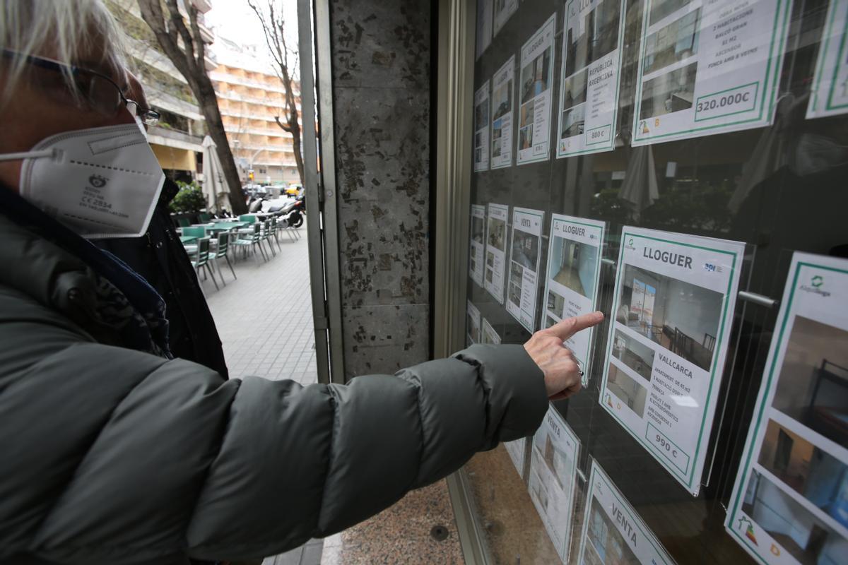 Una mujer mira anuncios de alquiler en una inmobiliaria de Barcelona.