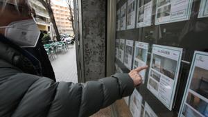Una mujer mira anuncios de alquiler en una inmobiliaria de Barcelona.