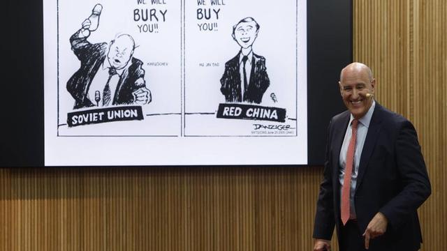 Mauro Guillén durante su conferencia, ayer, en la Cámara de Comercio de Oviedo. Detrás de él, la imagen de una viñeta de prensa que satiriza las estrategias económicas empleadas por la antigua Unión Soviética y China contra Estados Unidos: la primera dice «¡Te enterraremos!», y la segunda, «¡Te compraremos!». | LUISMA MURIAS