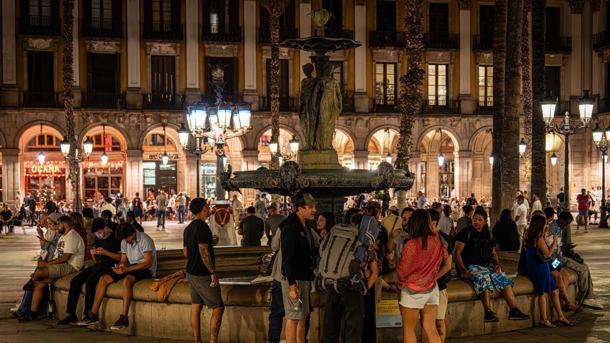 Diverses persones congregades a la font de la plaça Reial.