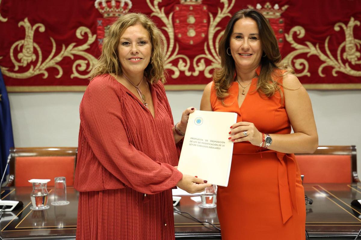La presidenta del Cabildo de Fuerteventura, Lola García (d), entrega a la tiular del Parlamento, Astrid Pérez, la reforma de la ley de cabildos en 2024.