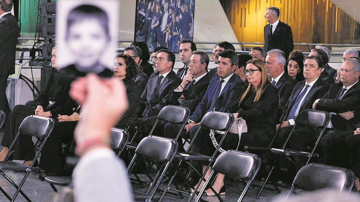 Una víctima enseña la foto de un familiar fallecido  ante Mazón en el Funeral de Estado.