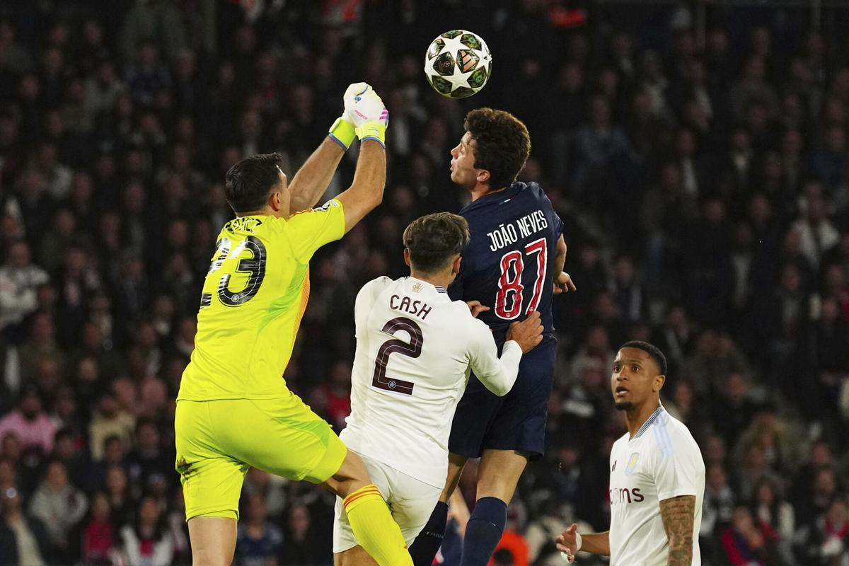 Aston Villa's goalkeeper Emiliano Martinez punches the ball away from PSG's Joao Neves, center, during the Champions League quarterfinal first leg soccer match between Paris Saint-Germain and Aston Villa at Parc des Princes stadium in Paris, Wednesday, April 9, 2025. (AP Photo/Aurelien Morissard)