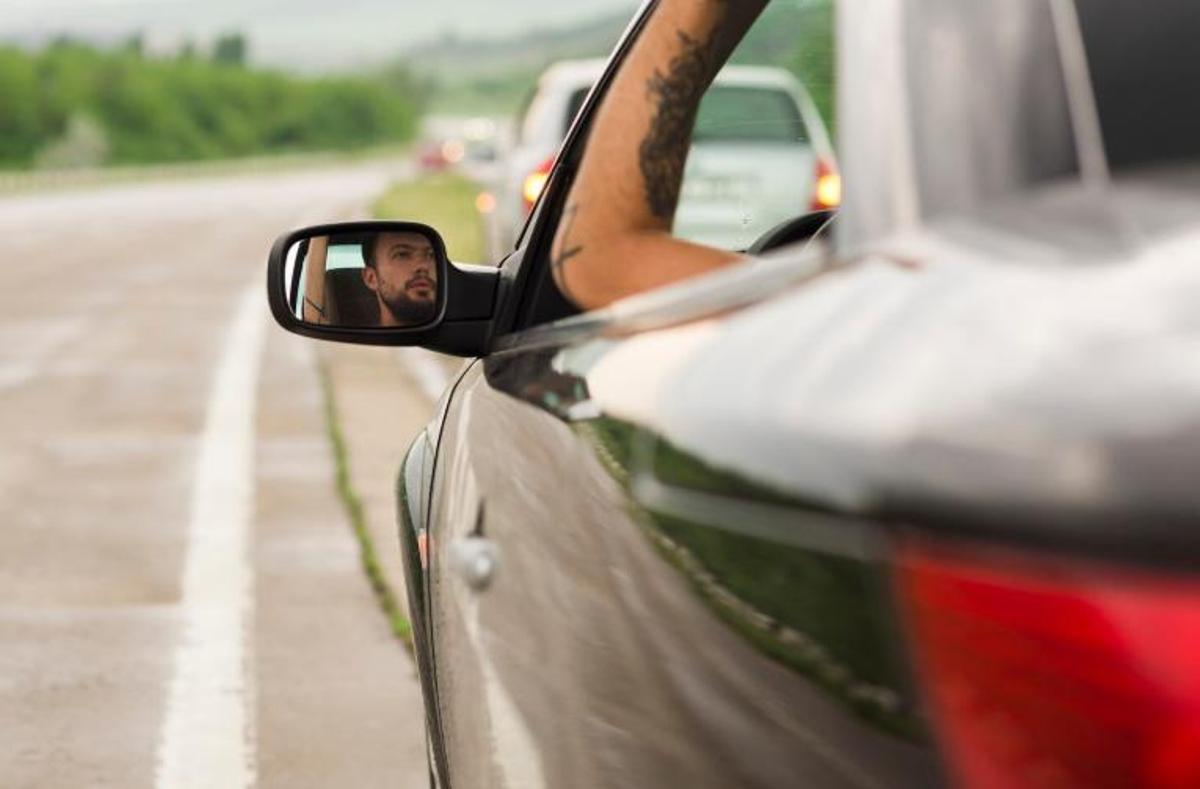 Un hombre visto desde el retrovisor de su coche.