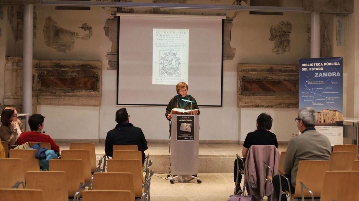 Una mujer en plena lectura del Quijote en el salón de actos. | ALBA PRIETO