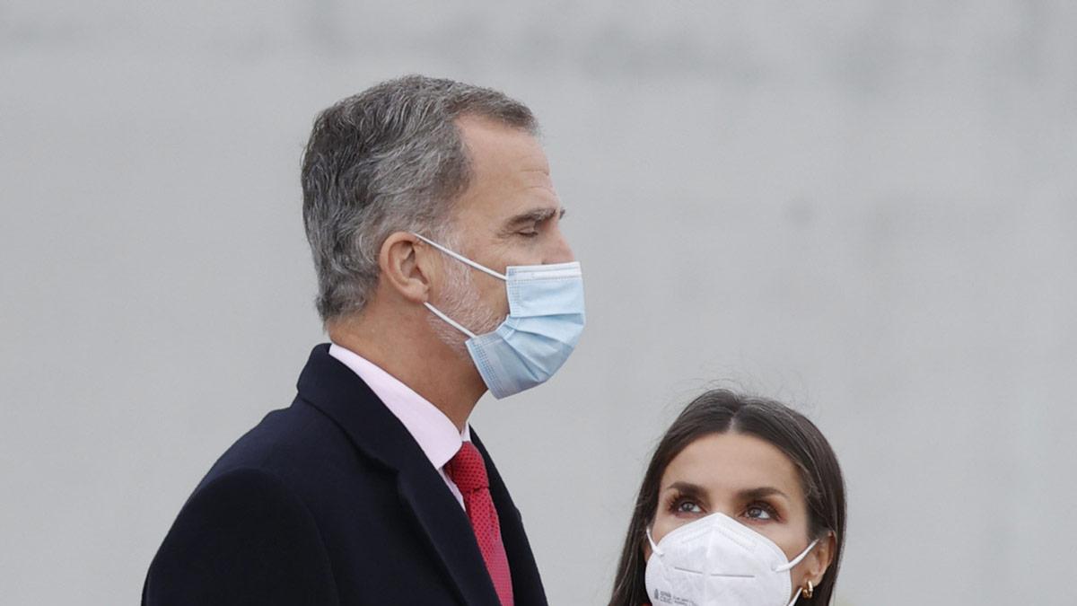 La reina Letizia, con abrigo rojo, y el rey Felipe en el aeropuerto de Barajas