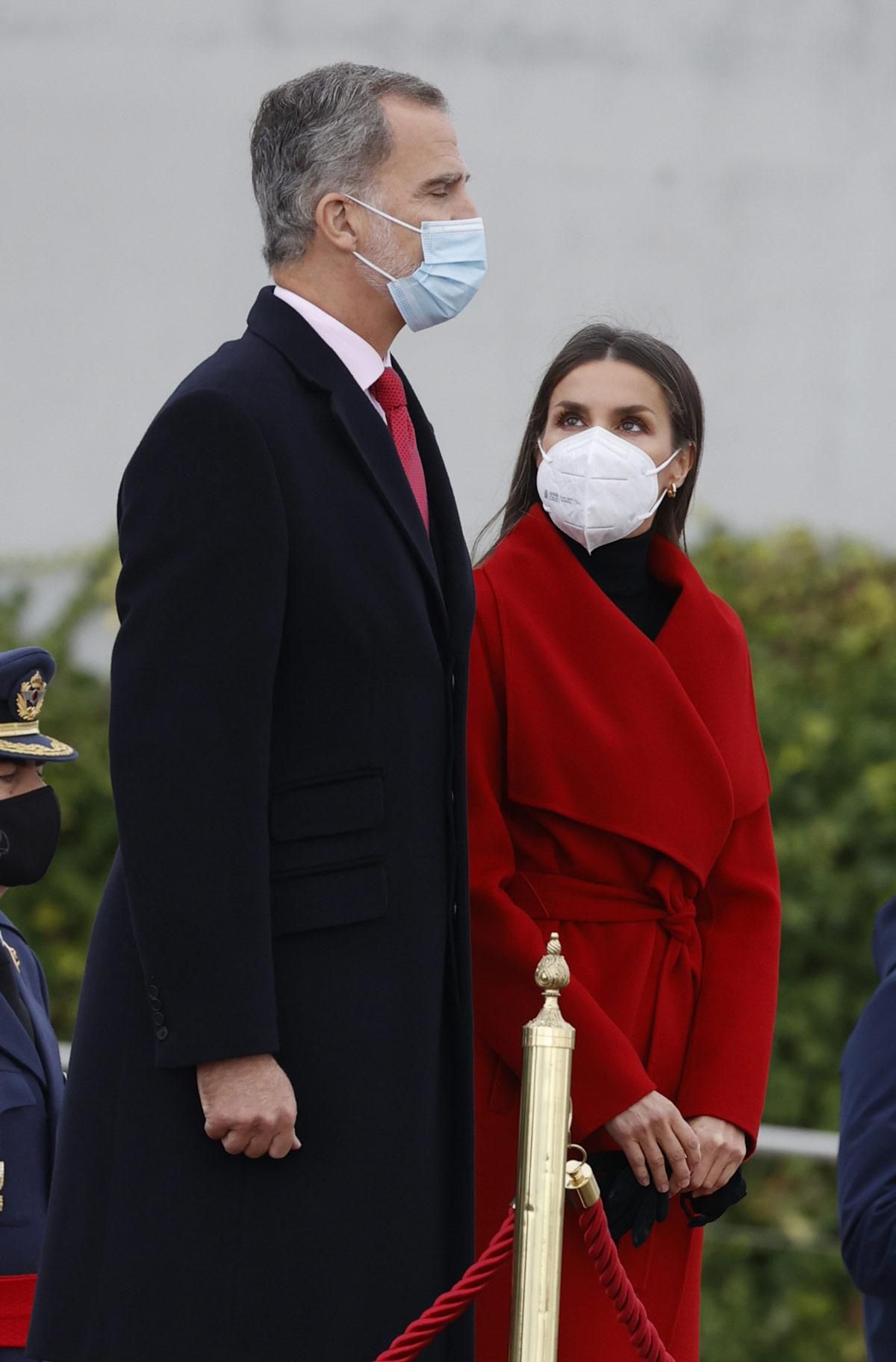 La reina Letizia, con abrigo rojo, y el rey Felipe en el aeropuerto de Barajas