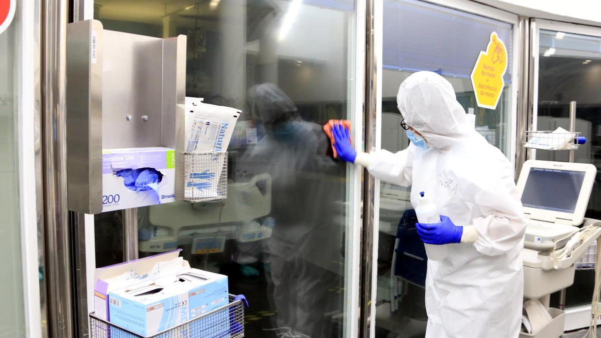 Una professional sanitària netejant els vidres d&#039;una UCI amb pacients amb covid-19 a l&#039;Hospital del Mar, en la pandèmia de coronavirus.