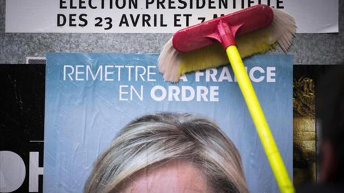 Un empleado del Frente Nacional pega un cartel electoral de Marine Le Pen al inicio de la campaña.