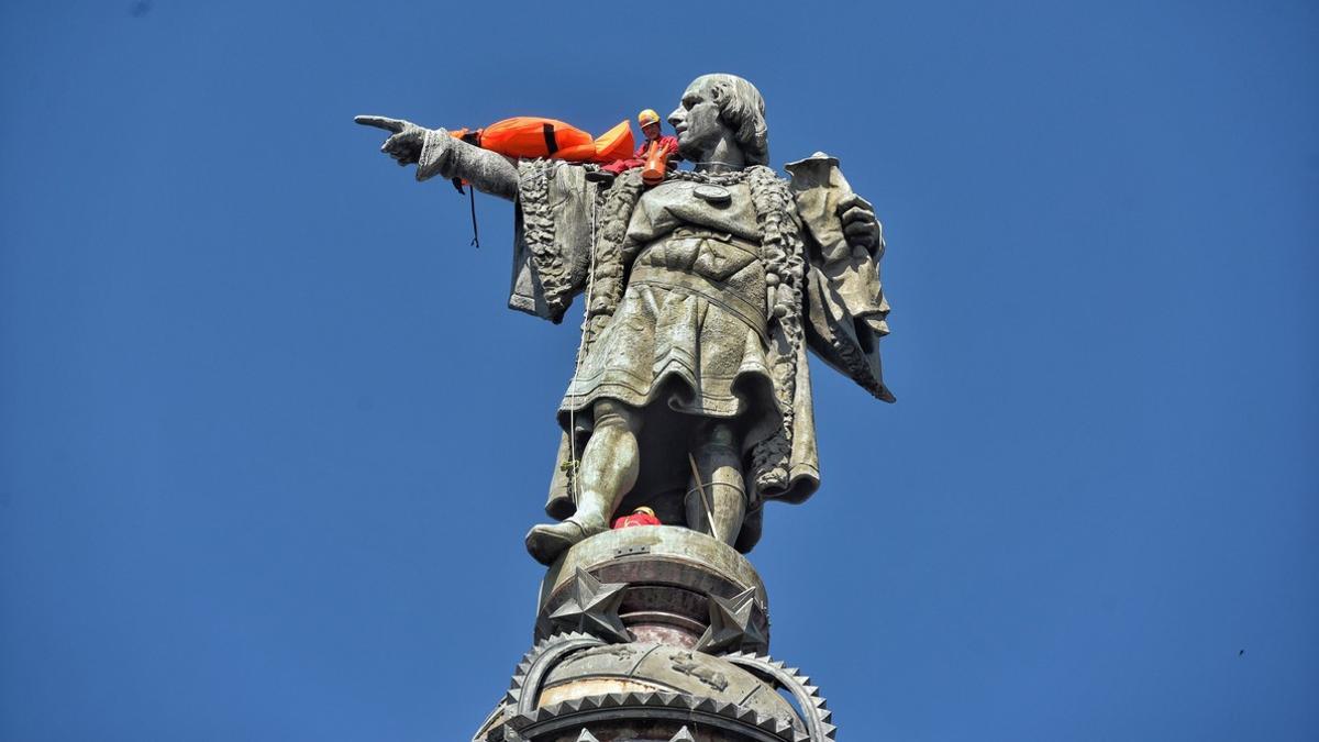 Un activista de Open Arms, encaramado a la estatua de Colón