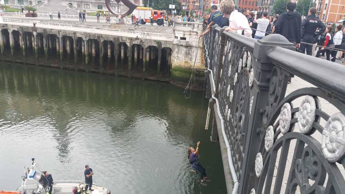 Bomberos izan a una feminista suspendida del puente del ayuntamiento de Bilbao como protesta contra las violaciones.