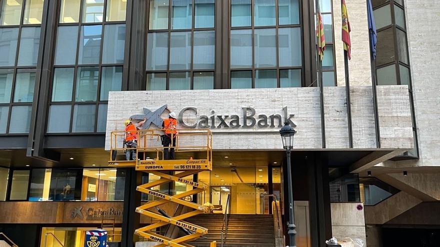 Operarios colocan el logo de CaixaBank en el edificio que albergaba la sede de Bankia en València