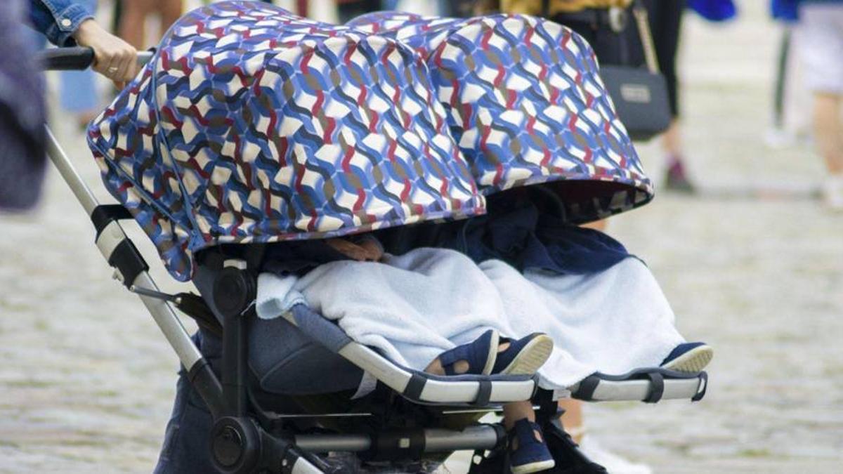 Dos bebés en un carrito con la ‘capota’ baja para protegerlos del sol .