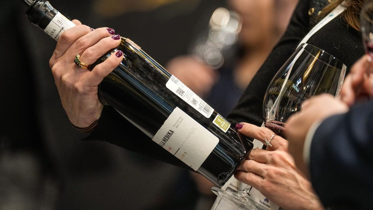 Una asistente a la Barcelona Wine Week sostiene una botella de vino tinto.