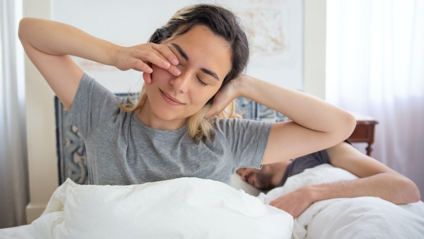 Una chica se despereza mientras su pareja sigue durmiendo