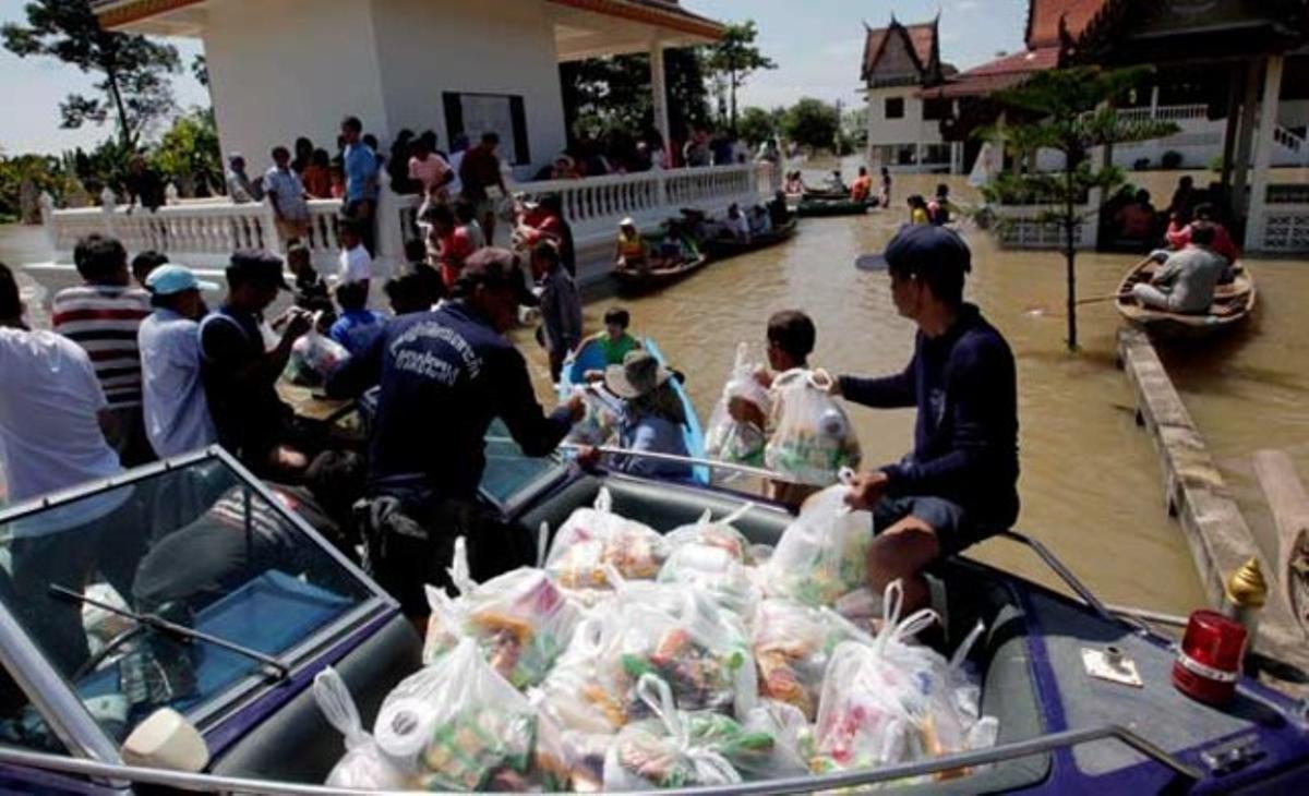 Veïns d’Ayutthaya, una ciutat al nord de Bangkok, reben medicines i menjar al temple local. Les inundacions provocades per la pluja al nord del país s’han estès fins a la capital.
