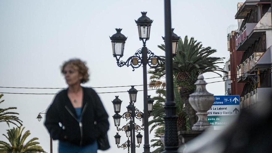 Una mujer camina por un paseo con farolas en La Laguna.