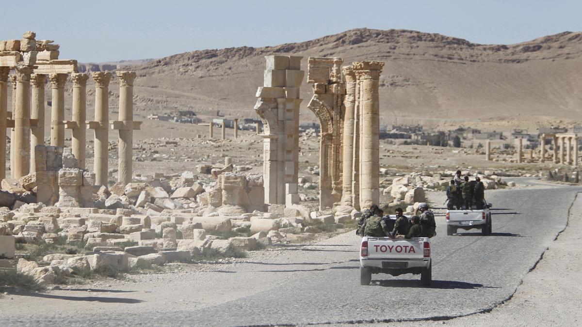 FILE PHOTO: Syrian army soldiers drive past the Arch of Triumph in the historic city of Palmyra, in Homs Governorate