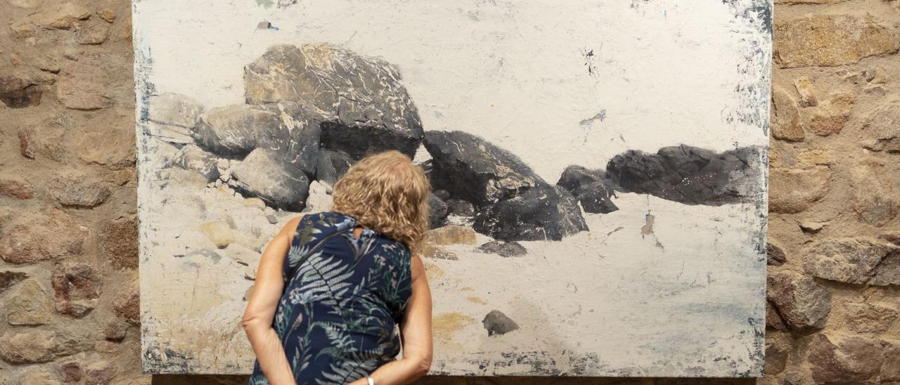Una dona mirant una d e les obres de Joan Mateu exposada al Castell de Benedormiens. | DAVID BORRAT/EFE