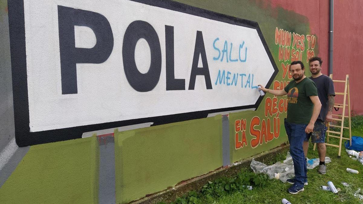 Fernando Argüelles, en primer término, con Chus Matos, ante un grafiti realizado en el Adaro de Sama.
