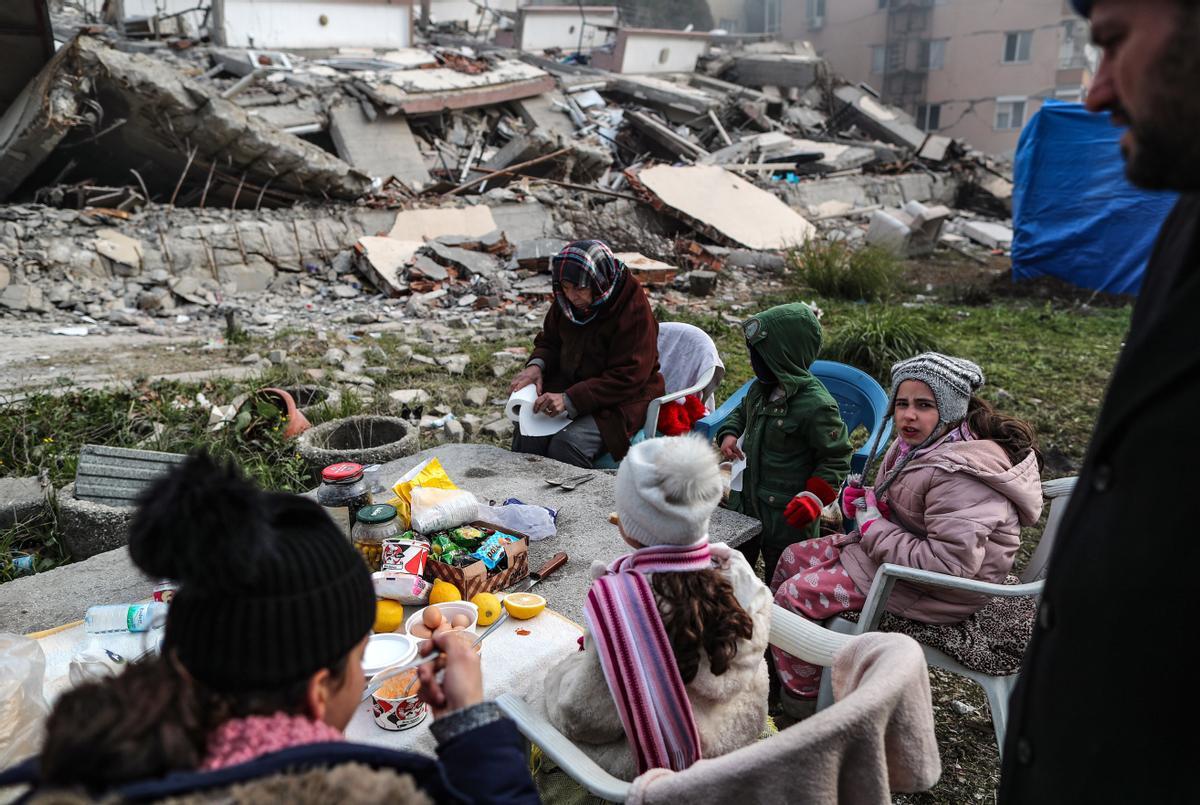  Personas desayunando junto a un edificio derrumbado tras el fuerte terremoto en Hatay, Turquía, el 11 de febrero de 2023. 