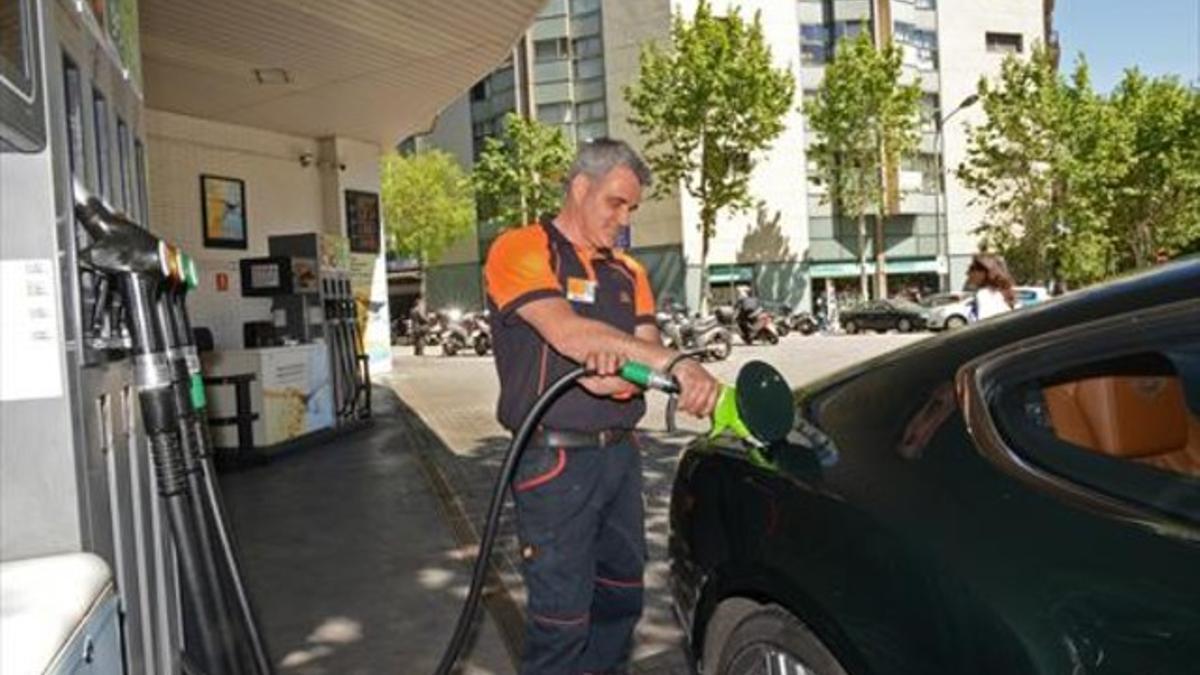 Un empleado llena un depósito en una gasolinera de Barcelona.