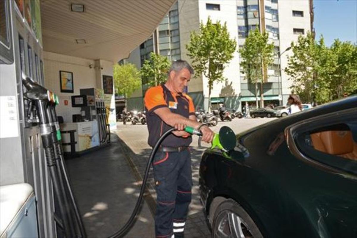 Un empleat omple un dipòsit en una gasolinera de Barcelona.