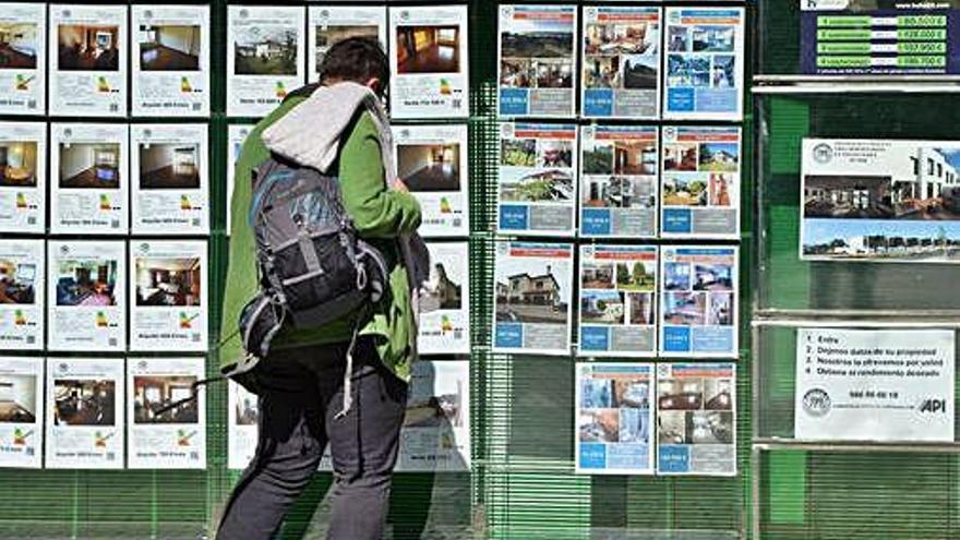 Un hombre observa las ofertas de pisos en venta y en alquiler en una inmobiliaria.