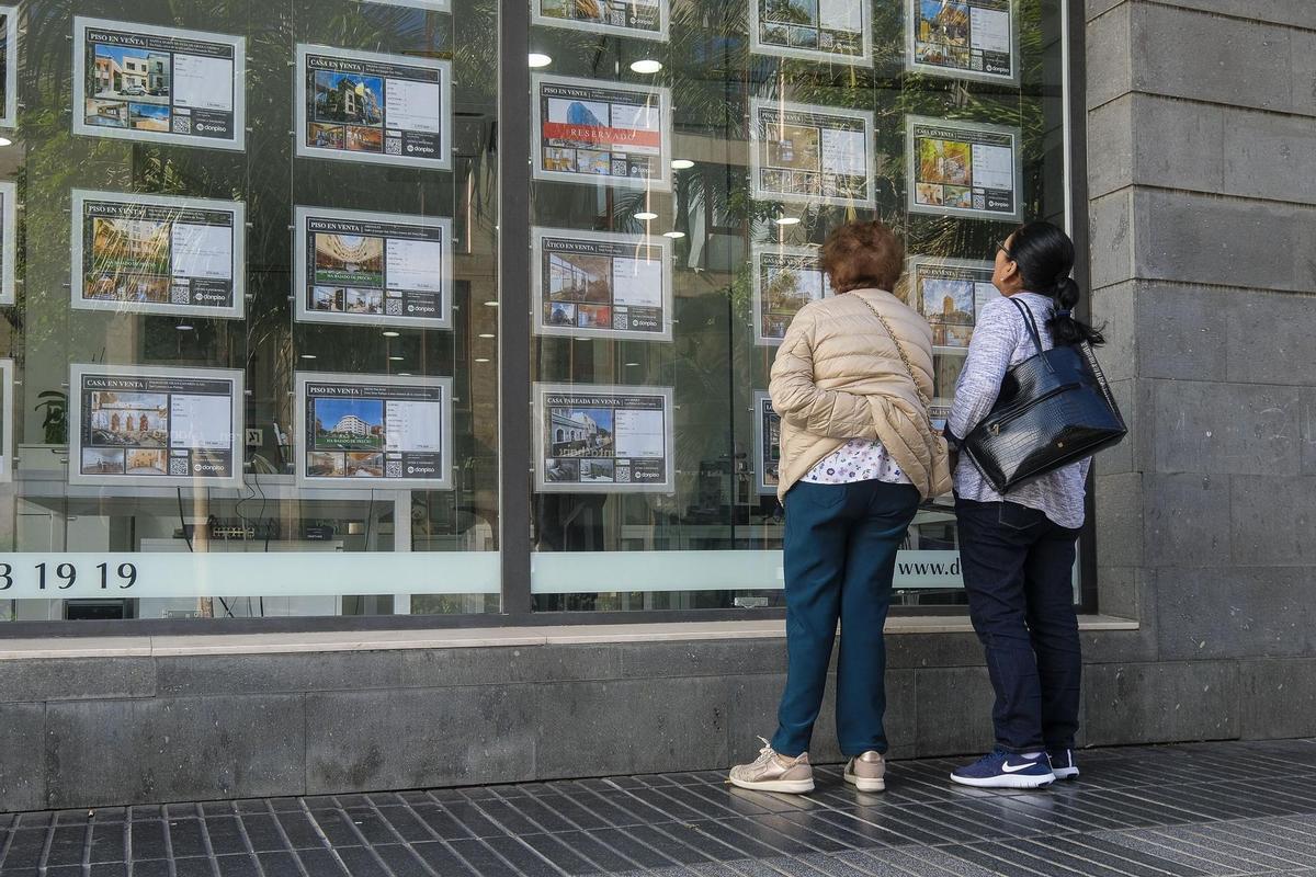 Dos mujeres miran anuncios de venta de casas en una inmobiliaria.