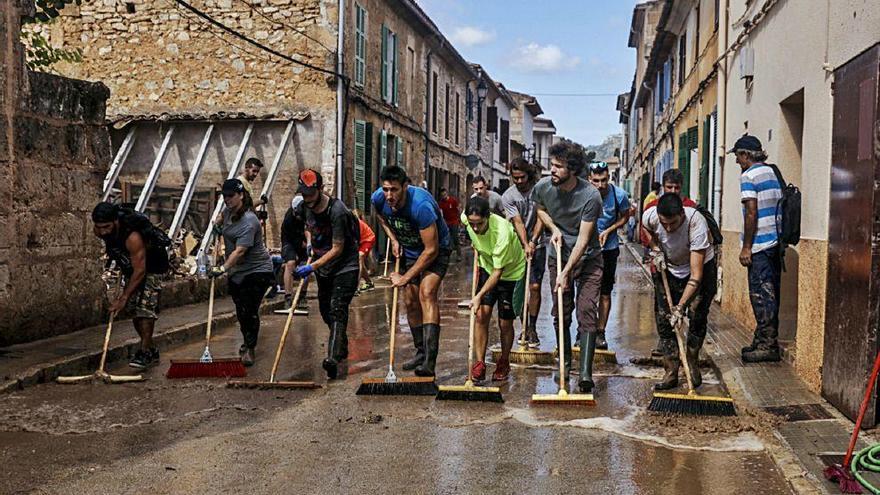 Un grupo de voluntarios ayuda a limpiar una calle de Sant Llorenç después de la riada.