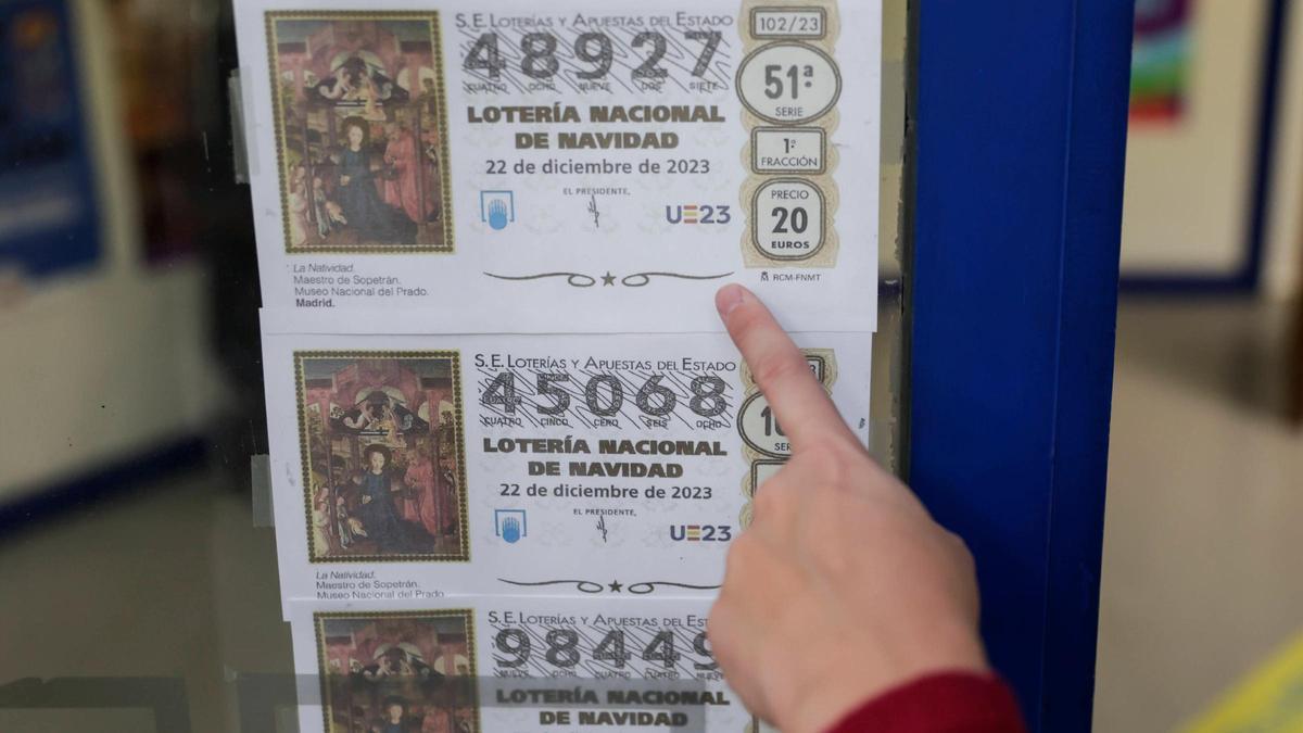 Una persona señala décimos de Lotería de Navidad de este año, en una administración de Loterías de Barcelona.