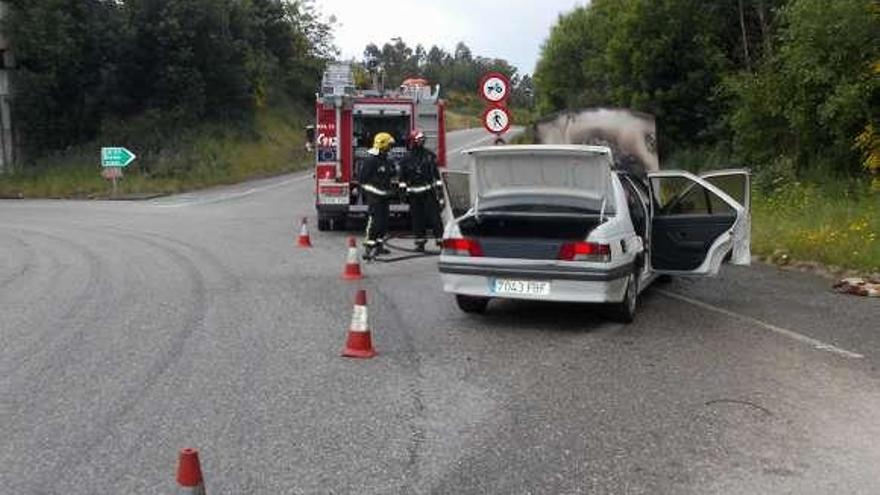 Los bomberos, con el coche incendiado en Ameixoada.