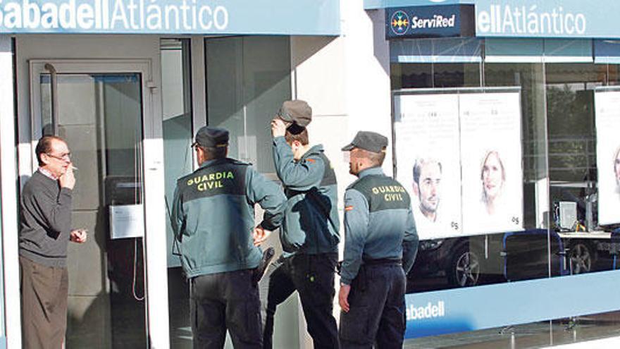 Tres guardias civiles en la puerta de la oficina bancaria, poco después del atraco.