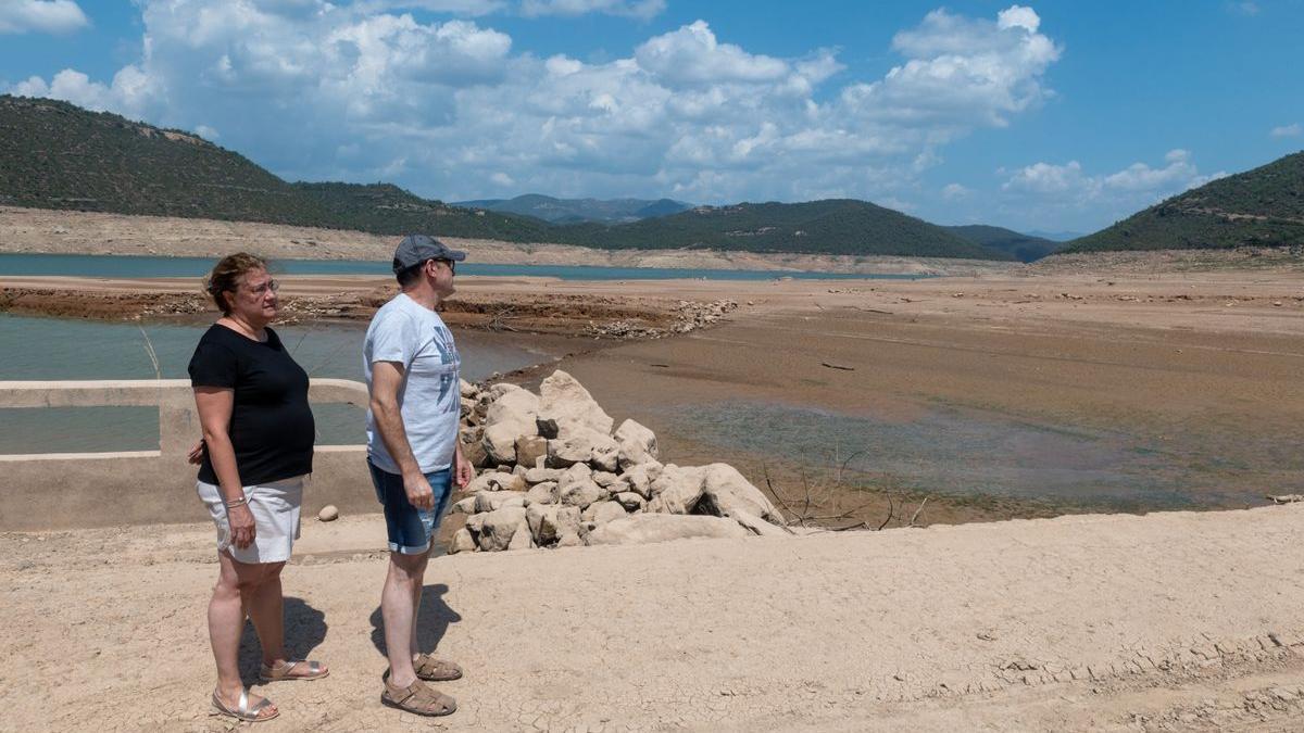 Dos vecinos aprovechan el bajo nivel del agua en el embalse de Rialb (Lleida) para ver el antiguo pueblo de Tiurana.