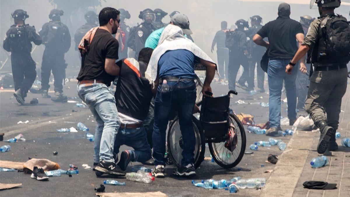 Unos hombres ayudan a un herido a subirse a una silla de ruedas durante las protestas.