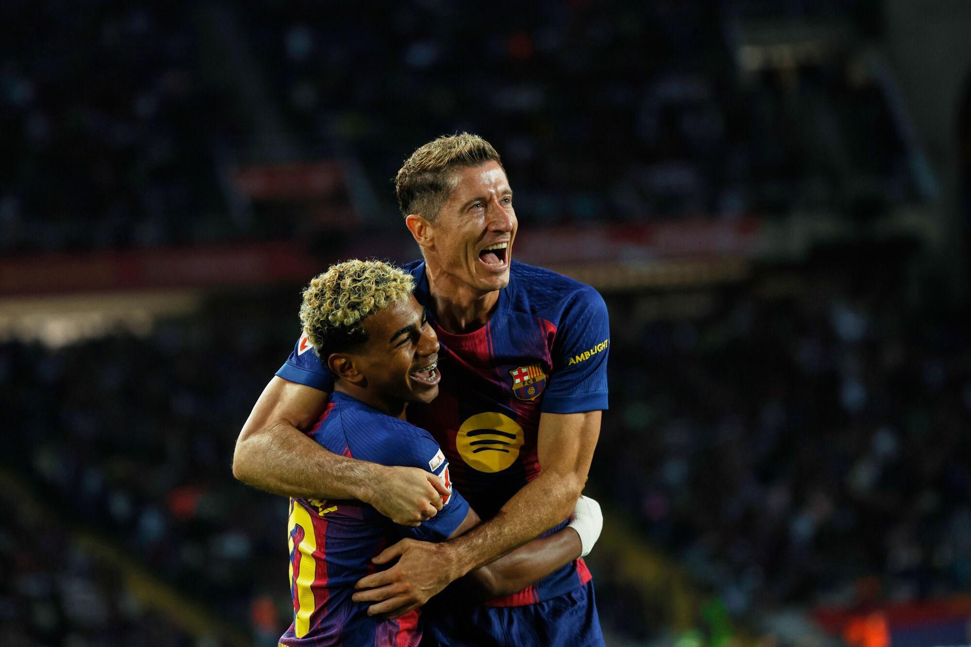 Barcelona's Robert Lewandowski, top, celebrates with Lamine Yamal scoring his side's first goal during a Spanish La Liga soccer match between FC Barcelona and Real Sociedad at the Lluis Companys Olympic Stadium in Barcelona, Spain, Sunday, Sept. 28, 2025. (AP Photo/Joan Monfort)
