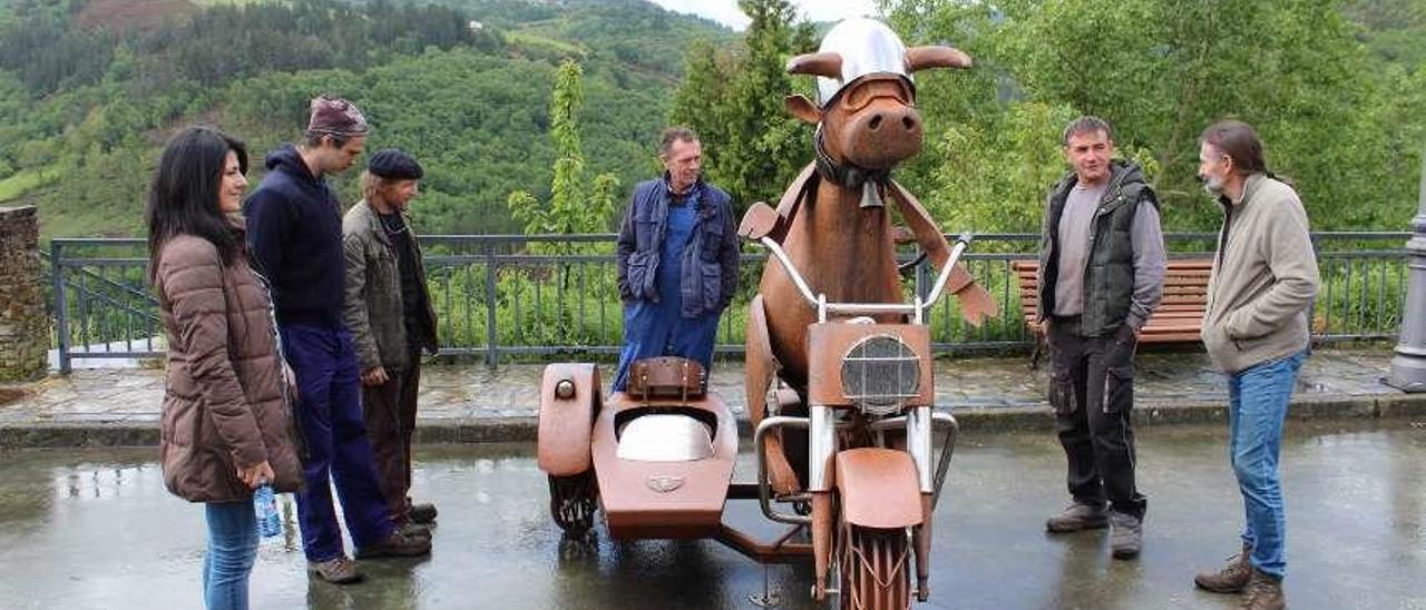 Algunos de los ferreiros asistentes observan la escultura de la vaca motera, creada en el último encuentro, que van a proteger de los vehículos rodeándola con unos bolardos.