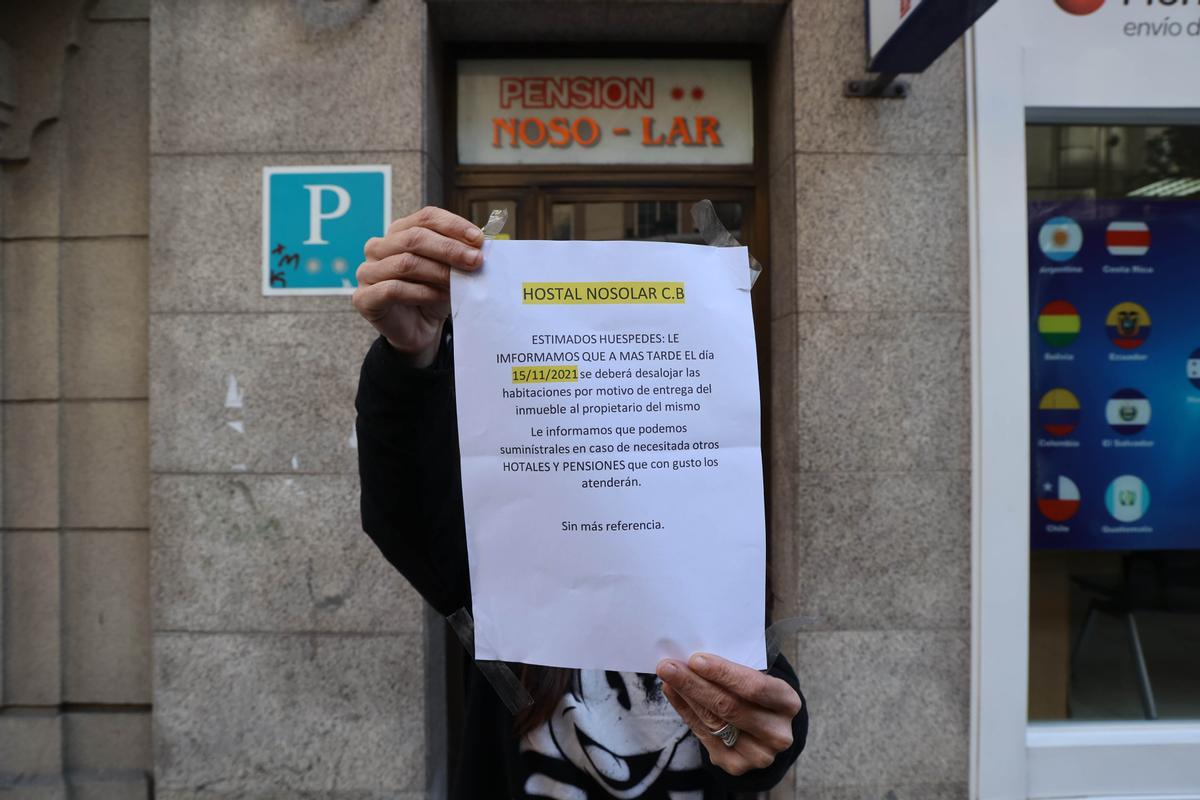 La inquilina sosteniendo el cartel que informa del desalojo del hostal