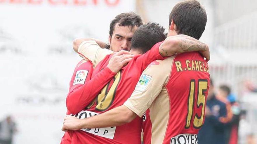 De las Cuevas, Nacho Novo y Canella, celebran un gol con la publicidad de Doyen Group en la espalda de la camiseta.