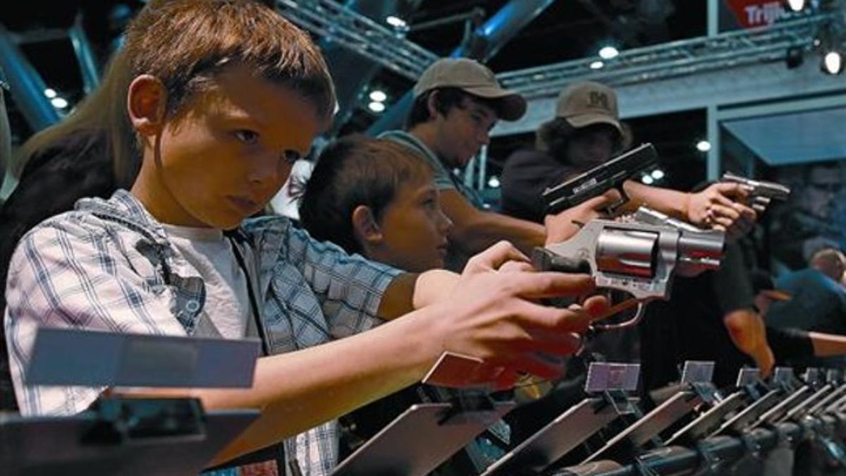 Unos niños prueban unas pistolas durante la celebración de la convención de la NRA, en Houston.