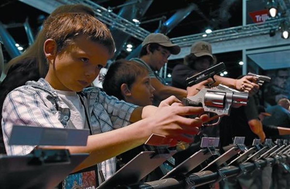 Uns nens proven unes pistoles durant la celebració de la convenció de la NRA, a Houston.