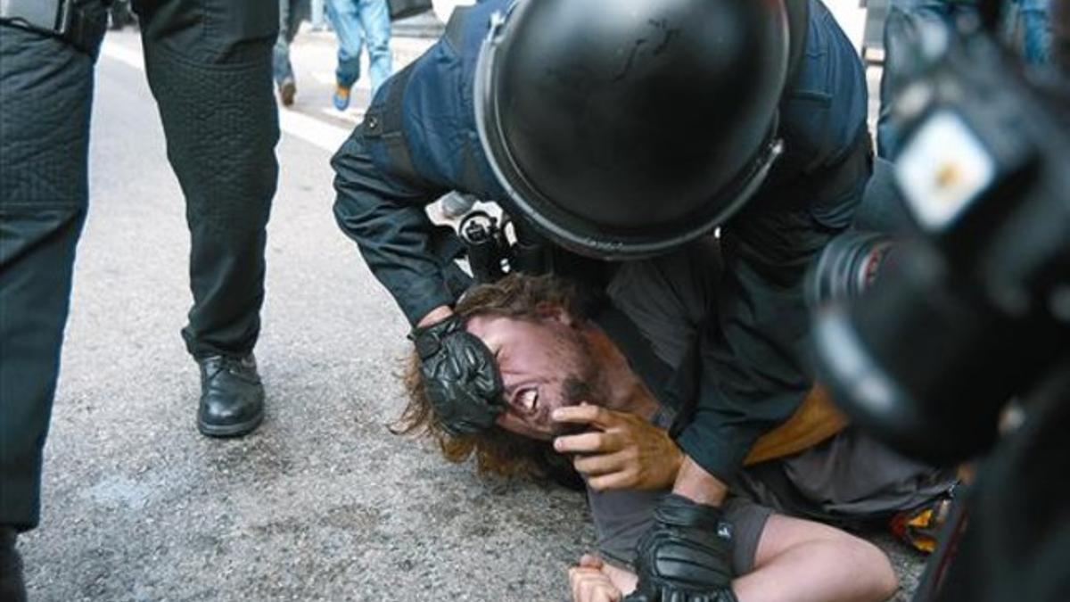 Un antidisturbios agarra en el suelo por la nariz a un indignado en la plaza de Catalunya, el 27 de mayo.