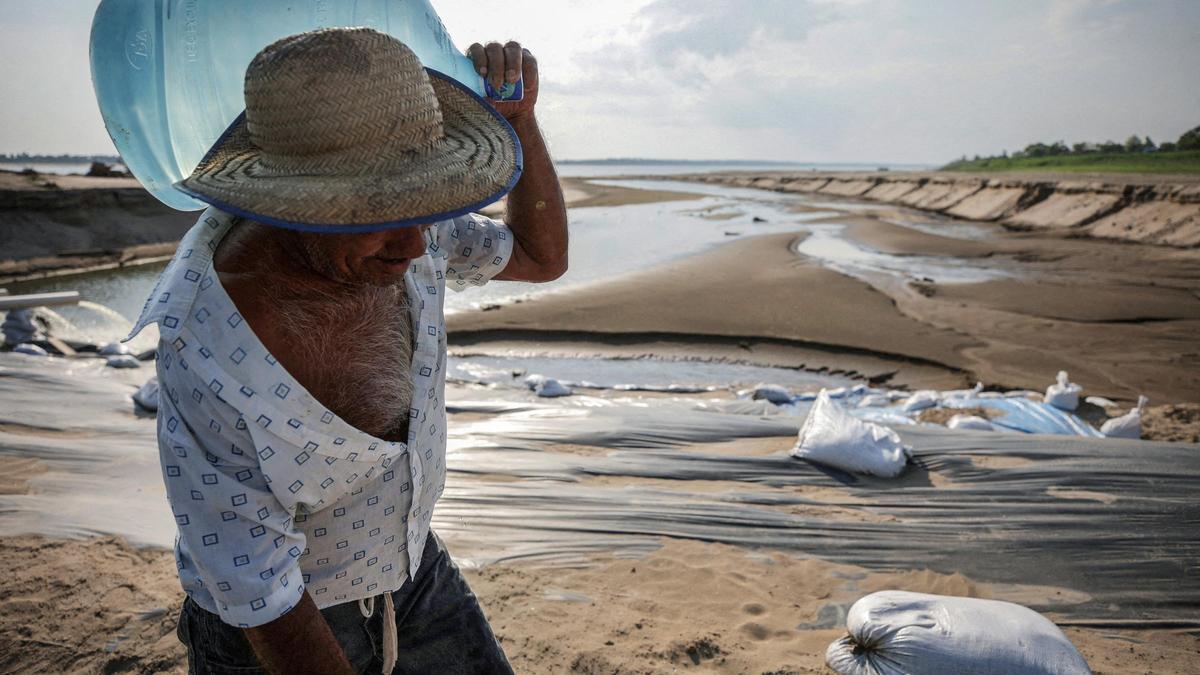 Un home porta una gerra d'aigua durant una sequera històrica en l'Amazones en el llit sec del riu *Paraua en *Careiro dona *Varzea, estat d'Amazones, el Brasil, aquest 2023.