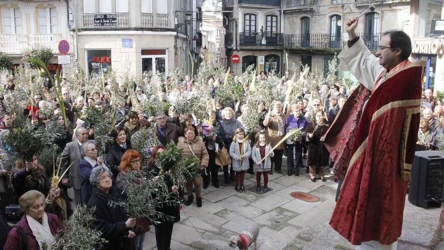 El párroco bendice los ramos y las palmas de los fieles concentrados en la Plaza de Reloj de Marín. // Santos Álvarez
