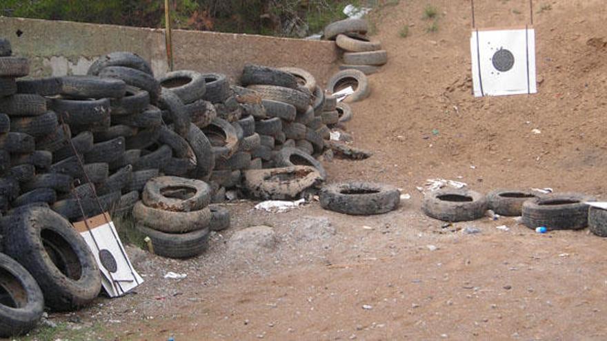 Neumáticos usados en un lateral de una galería de tiro, con la falda del monte detrás.