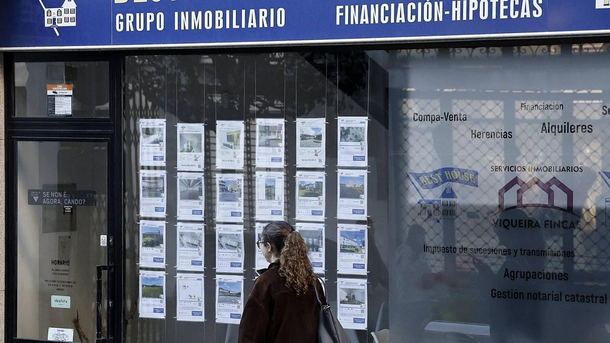 Una joven pasando ante el escaparate de una inmobiliaria en Santiago.
