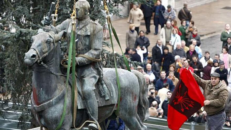 Un ciudadano exhibe una bandera falangista, tras subirse al andamio en el que trabajan los operarios para retirar la estatua ecuestre de Francisco Franco de la plaza del Ayuntamiento de Santander. Esta figura de bronce, que ha presidido la principal plaza de Santander desde 1964, era la última representación de Franco a caballo que quedaba en una vía pública en España, tras la retirada de las de Madrid y Valencia.