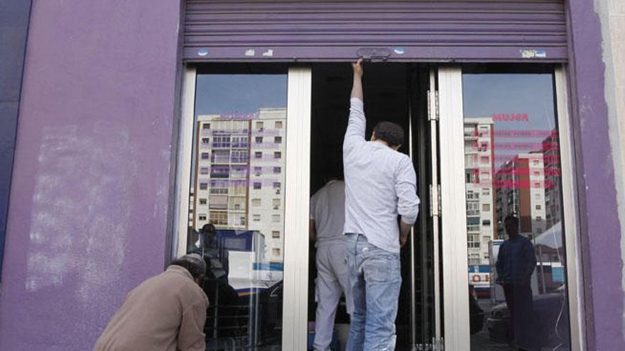 Un comerciante abre la puerta de su negocio.